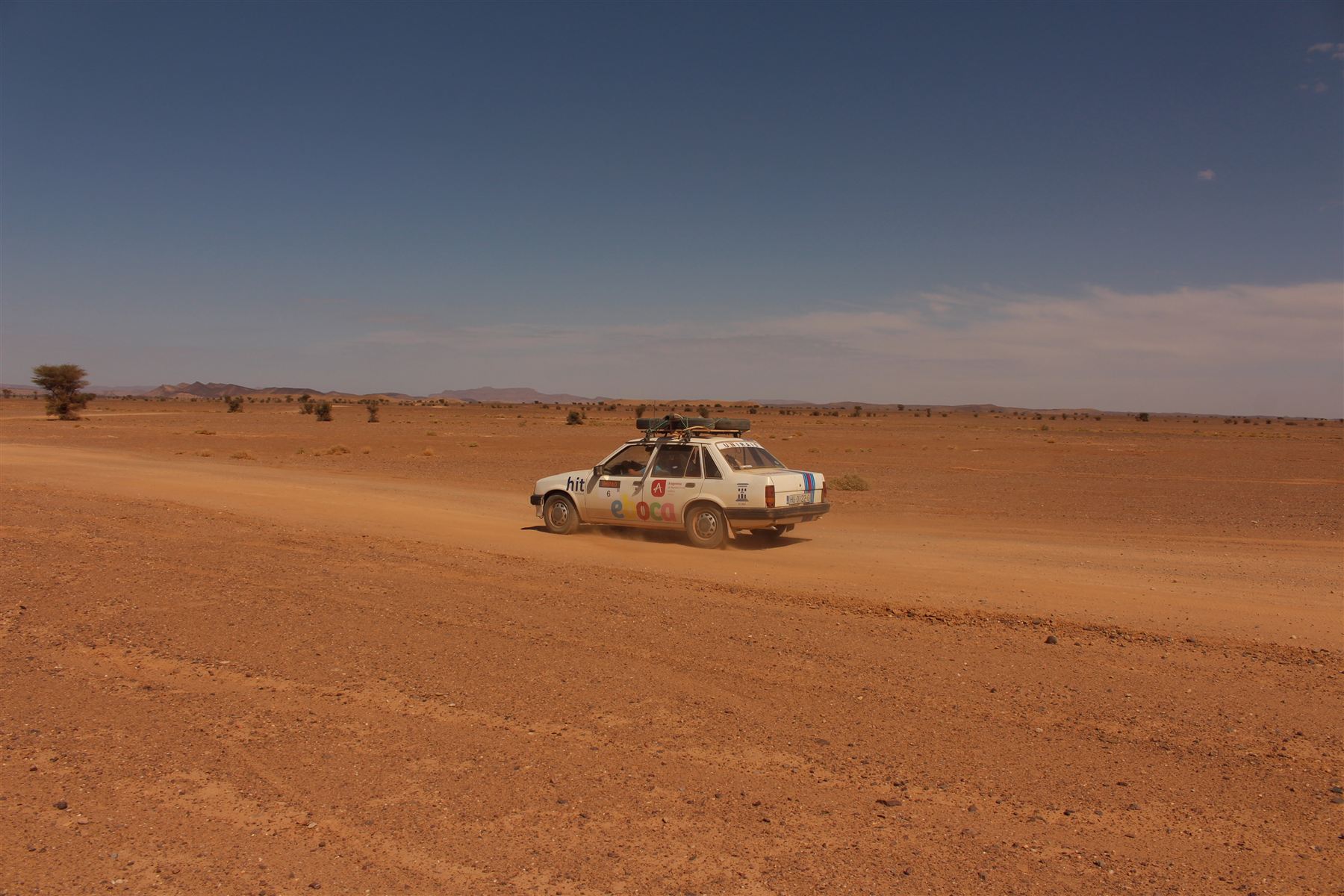 Vehículo del equipo cruzando el desierto en solitario bajo un cielo despejado