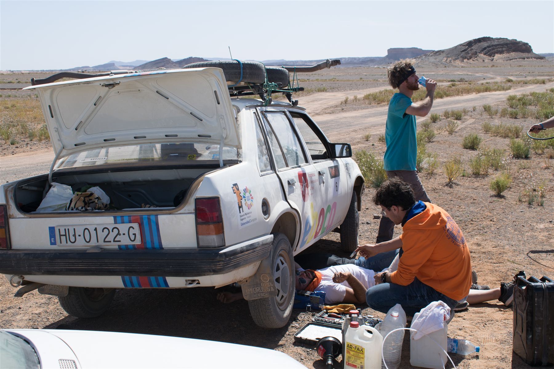 El equipo reparando el vehículo durante una parada en el desierto