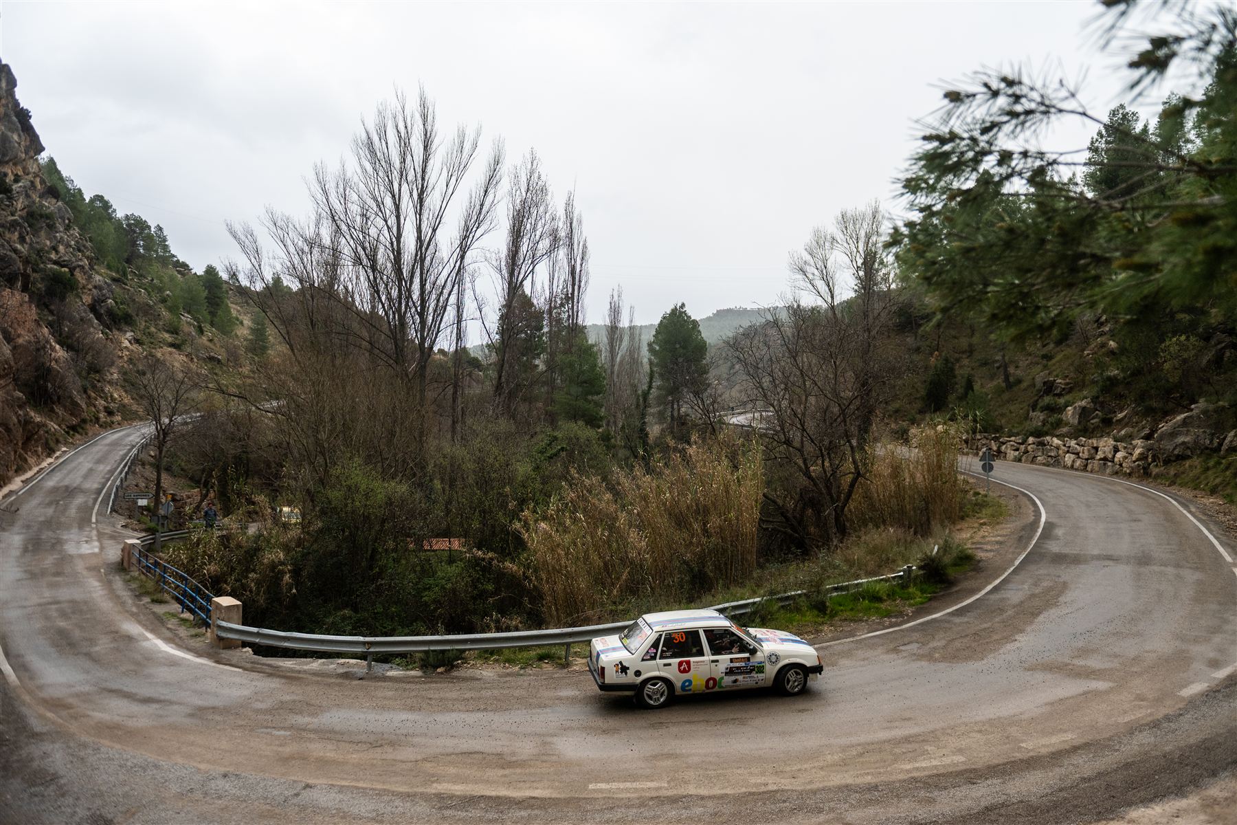 Vista aérea de un coche de rally en una curva de horquilla de montaña